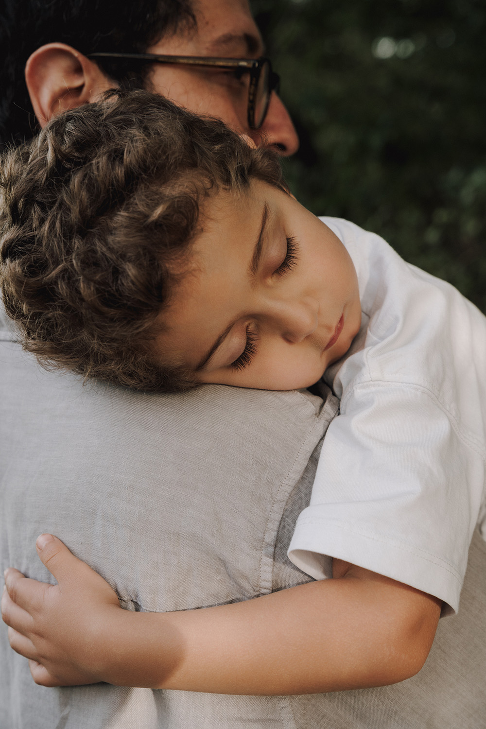 Familienfotos Wien. Ein Vater hält sein schlafendes Kind liebevoll im Arm während eines Family Fotoshootings in Wien.