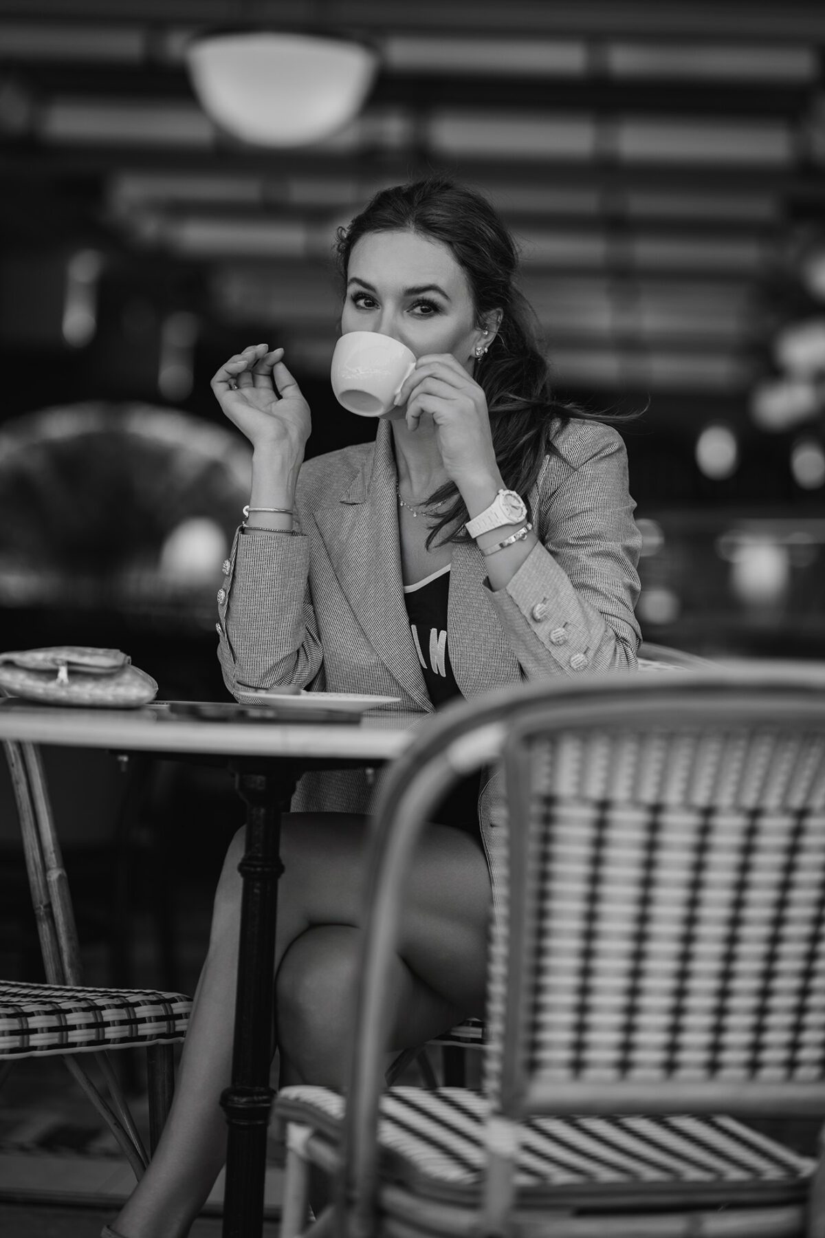 Portrait Fotoshooting. Business Portrait Wien. Black and white fashion portrait at a Monaco café – stylish moment with coffee, pastry, and architectural ambiance.