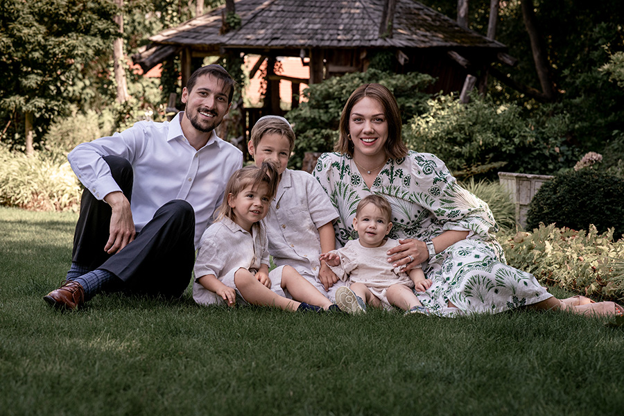 Familie sitzt eng beisammen auf einer grünen Wiese im Garten, ein harmonischer Moment voller Nähe und Ruhe, einfühlsam festgehalten von einem Familien Fotograf Wien.