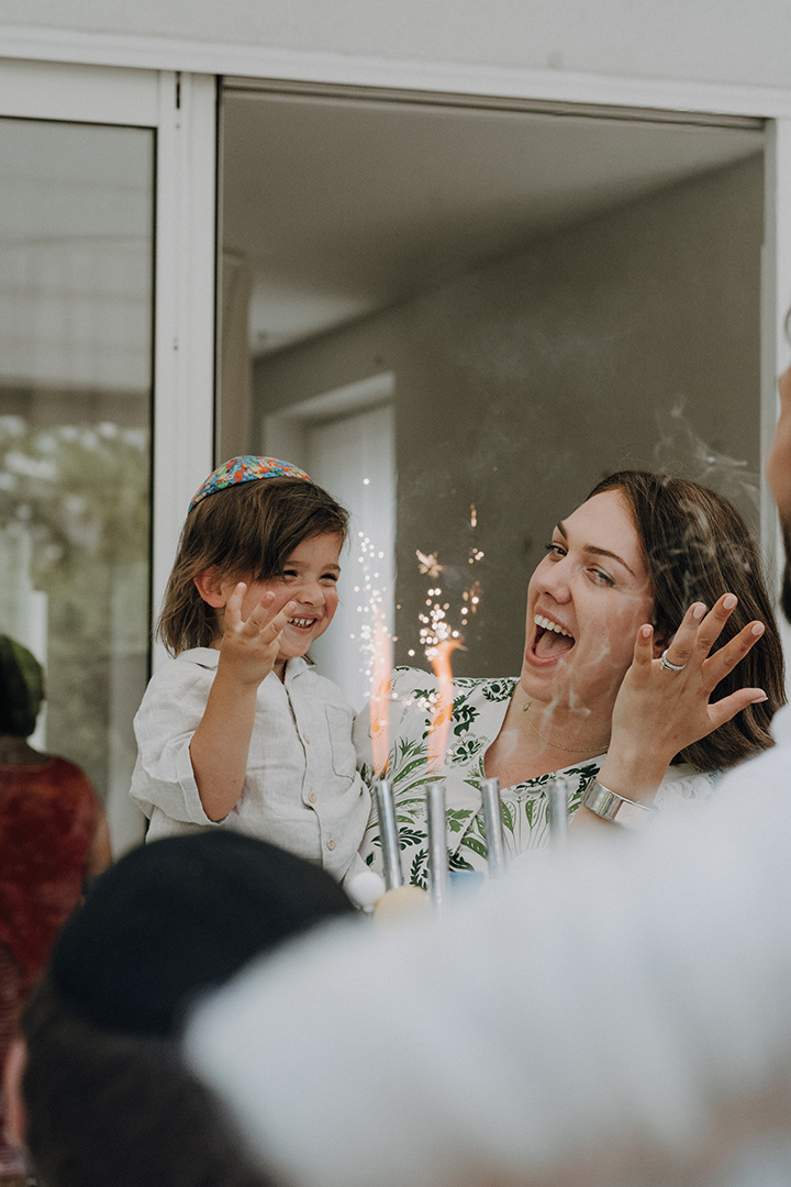 Kind und Mutter lächeln einander bei einer Feier mit funkelnden Kerzen an – ein liebevoller Moment, einfühlsam festgehalten von einem Familien Fotograf Wien.