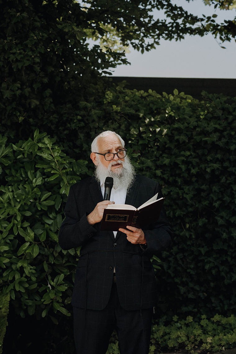 Ein Rabbiner liest bei einer feierlichen Veranstaltung im Grünen aus einem Buch und spricht ins Mikrofon, stimmungsvoll dokumentiert von einem Eventfotograf Wien.