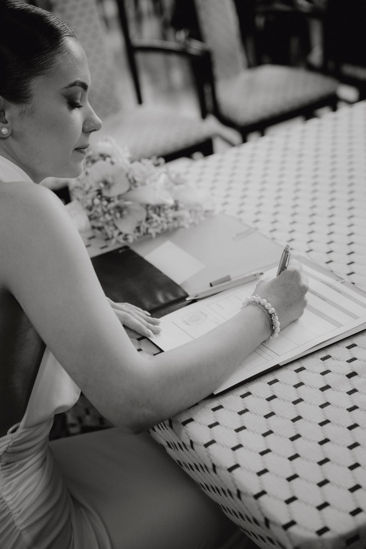 Hochzeitsfoto der Braut beim Unterschreiben der Unterlagen während einer eleganten Standesamthochzeit.