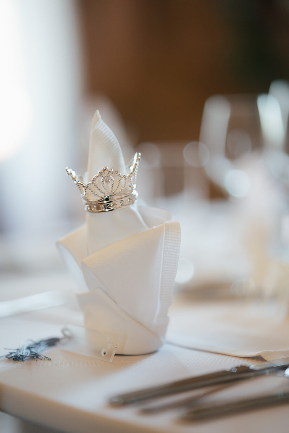Luxus Hochzeitsdetails in Wien – elegant gefaltete Serviette mit silberner Krone als Tischdekoration, fotografiert von Hochzeitsfotografin aus Wien.