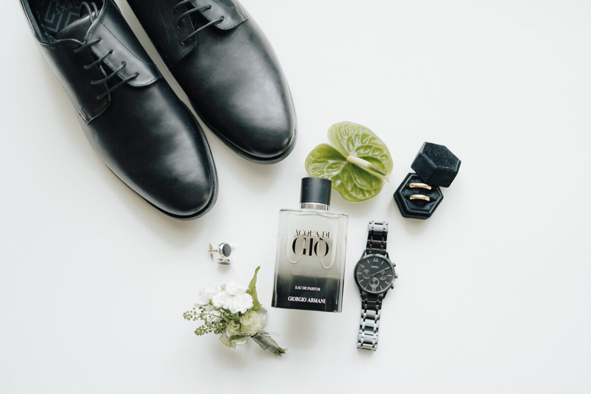 Flatlay mit Herren‑Accessoires, Ringen, Uhr und Parfum – stilvolle Hochzeitsvorbereitungen Wien.